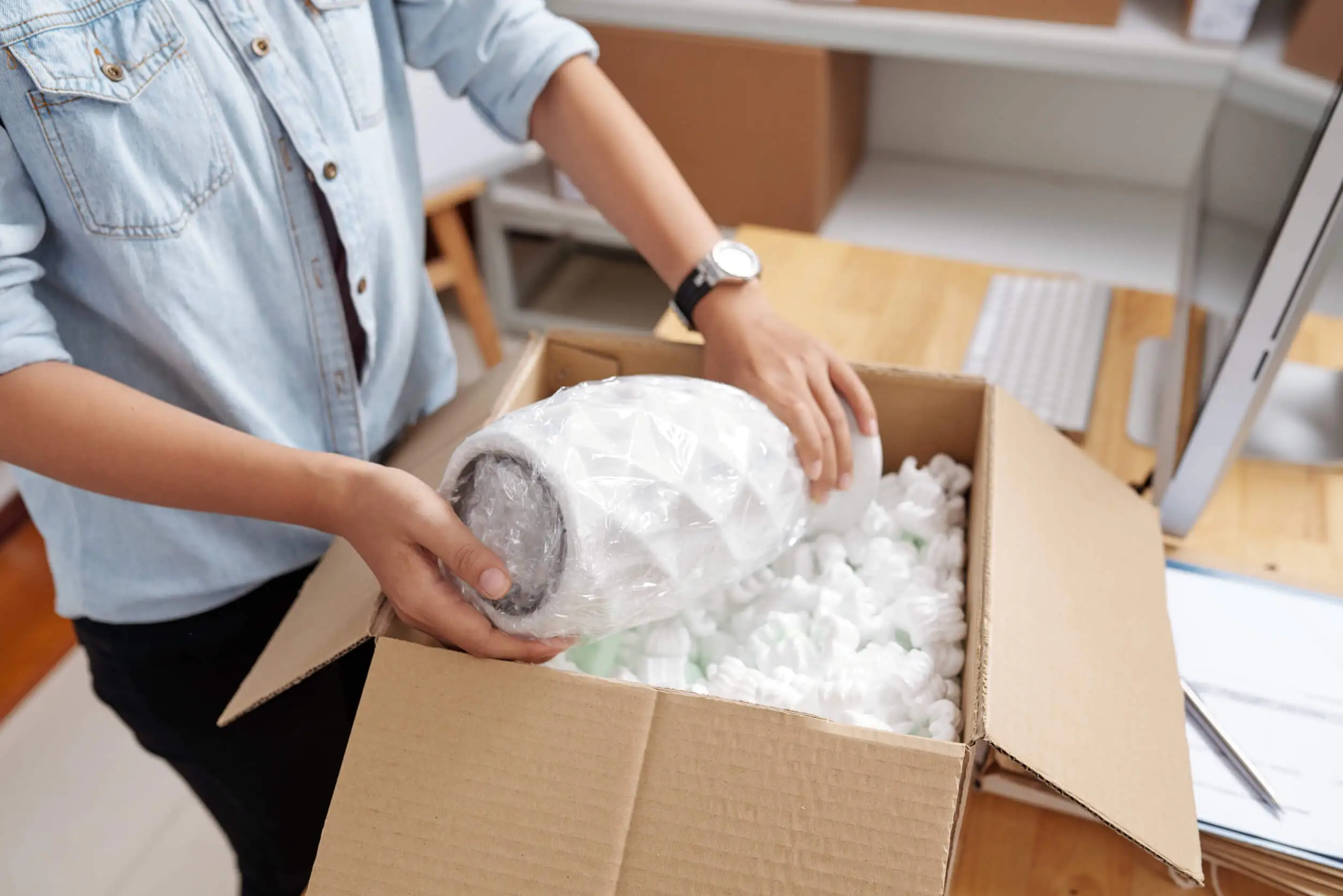 Person carefully unboxing a precious ceramic piece protected by eco-friendly packing materials
